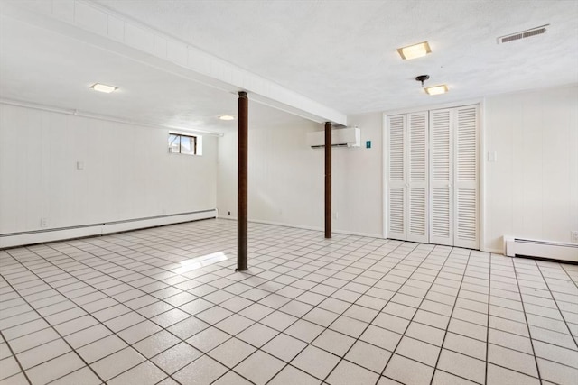 basement with a baseboard heating unit, light tile patterned floors, and a wall unit AC