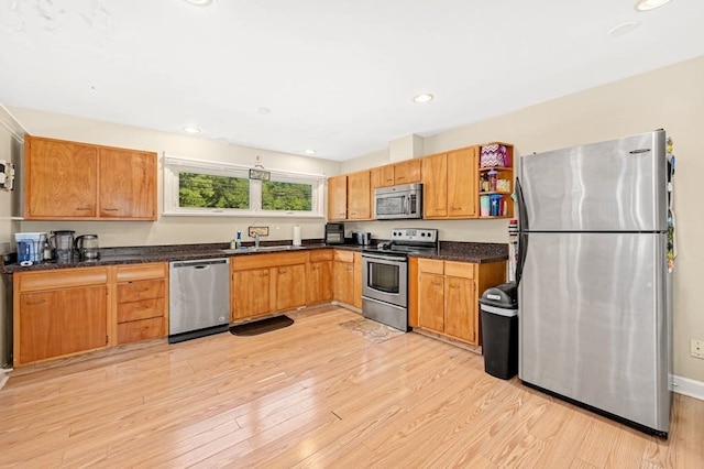 kitchen featuring dark stone countertops, light wood-type flooring, sink, and appliances with stainless steel finishes