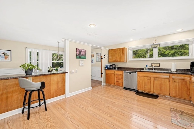 kitchen featuring light hardwood / wood-style flooring, hanging light fixtures, dark stone countertops, and stainless steel dishwasher