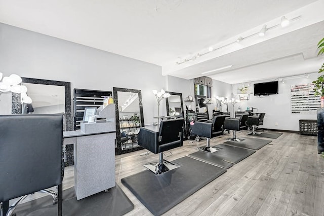 workout area with rail lighting and wood-type flooring