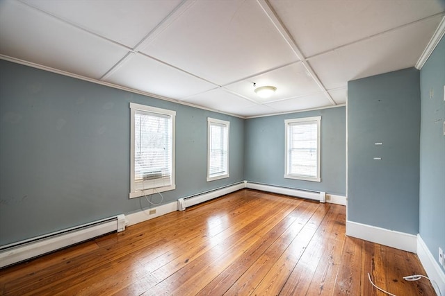 unfurnished room featuring baseboard heating and hardwood / wood-style flooring