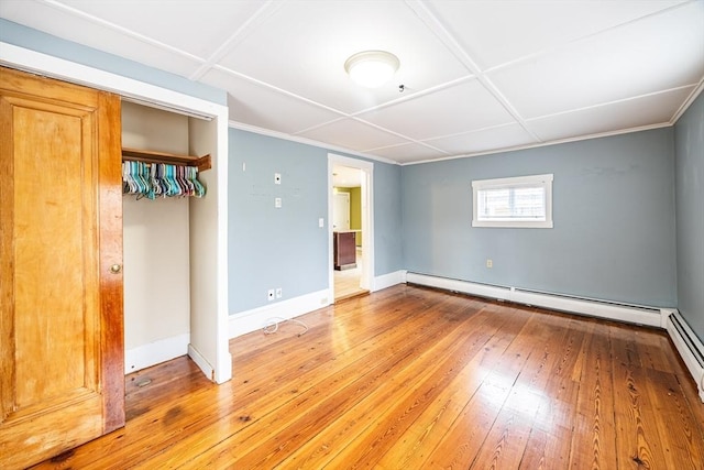 unfurnished bedroom with baseboard heating, light hardwood / wood-style flooring, and a closet