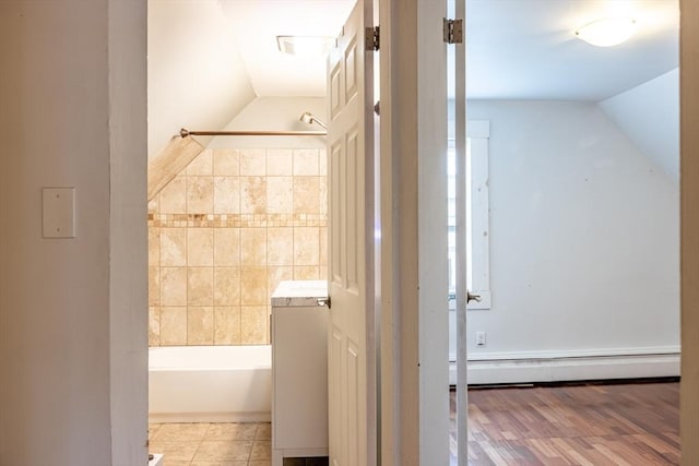 bathroom with a bathtub, a baseboard radiator, and lofted ceiling