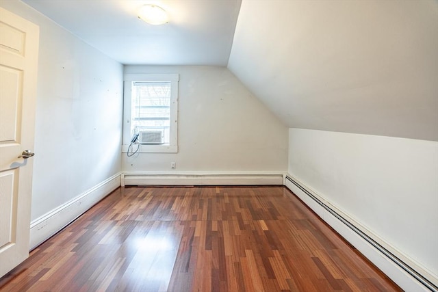 additional living space with vaulted ceiling, cooling unit, baseboard heating, and dark wood-type flooring