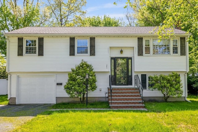 bi-level home featuring an attached garage, a front yard, and asphalt driveway