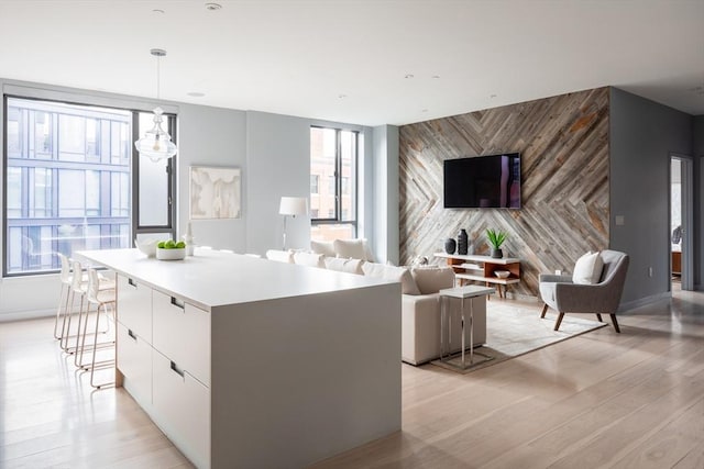 kitchen with a breakfast bar area, light hardwood / wood-style flooring, hanging light fixtures, a kitchen island, and white cabinets