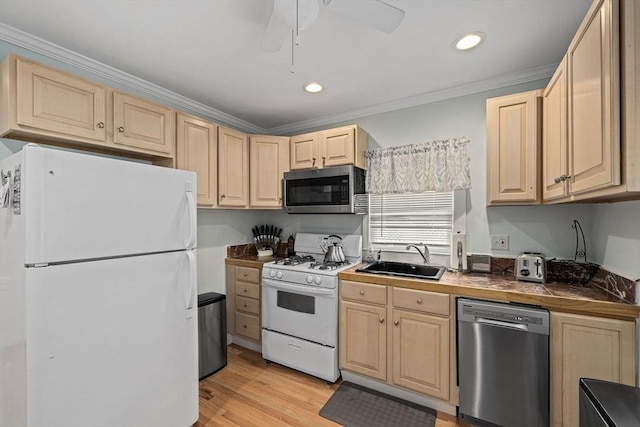 kitchen with appliances with stainless steel finishes, tile countertops, sink, ornamental molding, and light hardwood / wood-style floors