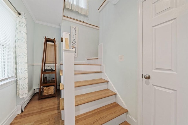 stairs with baseboard heating, ornamental molding, and hardwood / wood-style floors