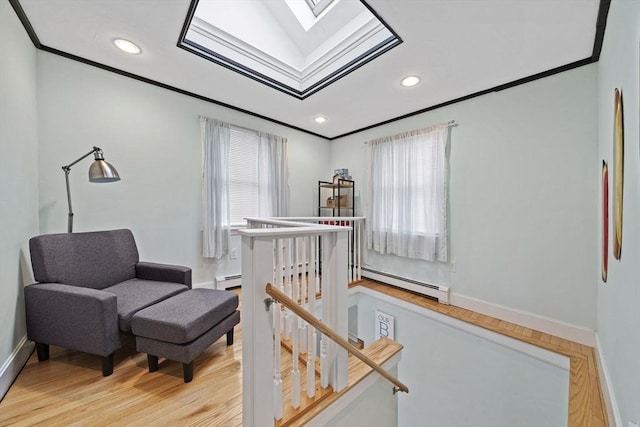 sitting room featuring crown molding, a baseboard heating unit, light hardwood / wood-style flooring, and a skylight