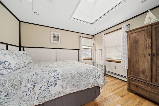 bedroom with crown molding, a baseboard radiator, and light hardwood / wood-style floors