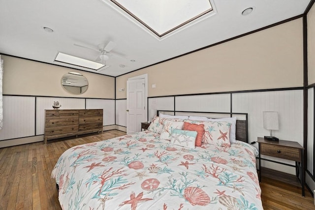 bedroom featuring ceiling fan, ornamental molding, a skylight, and hardwood / wood-style floors