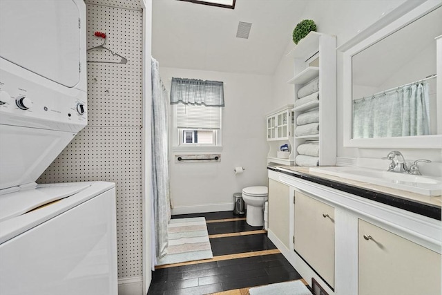 bathroom with stacked washer and dryer, vanity, hardwood / wood-style floors, and toilet