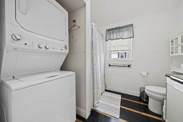 clothes washing area featuring stacked washer and clothes dryer and dark hardwood / wood-style floors