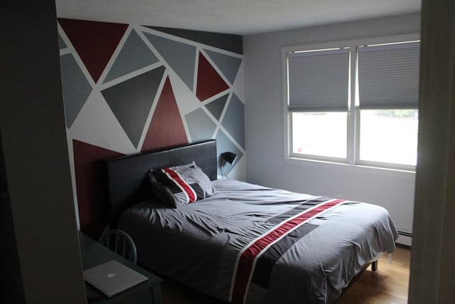 bedroom featuring hardwood / wood-style floors and a baseboard heating unit