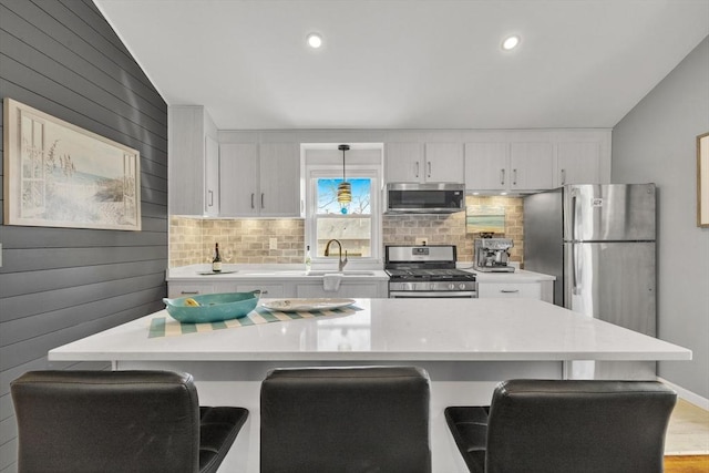 kitchen featuring a sink, a breakfast bar area, light countertops, and appliances with stainless steel finishes