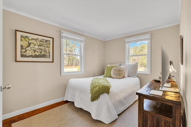 bedroom featuring baseboards, crown molding, and wood finished floors