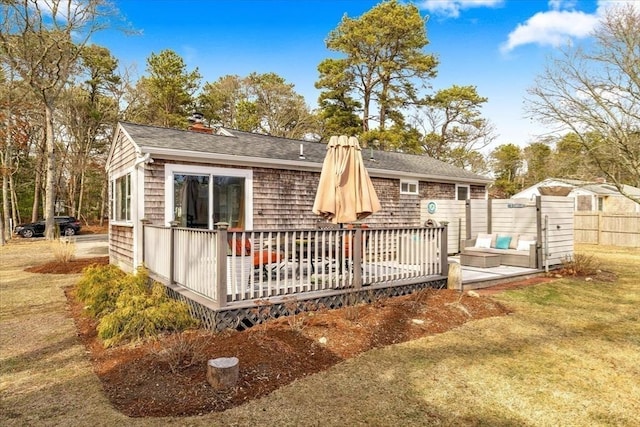 back of house with fence, a chimney, a shingled roof, and a deck