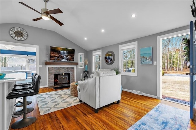 living area with ceiling fan, visible vents, vaulted ceiling, and wood finished floors
