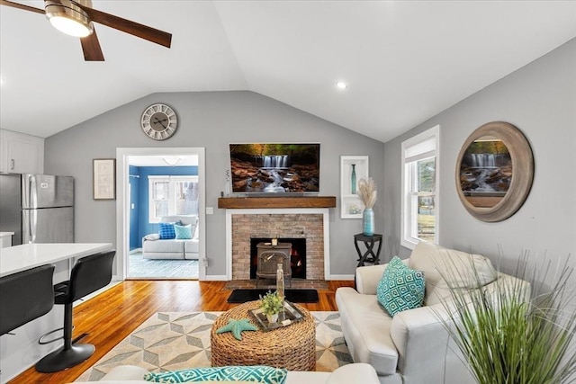 living room featuring baseboards, lofted ceiling, ceiling fan, and light wood-style flooring