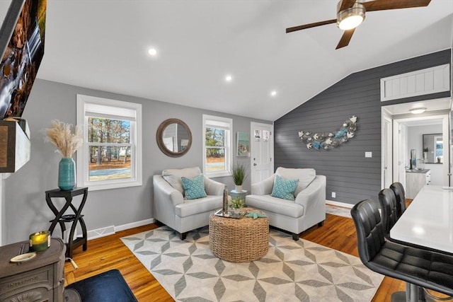 living area featuring baseboards, lofted ceiling, ceiling fan, and wood finished floors