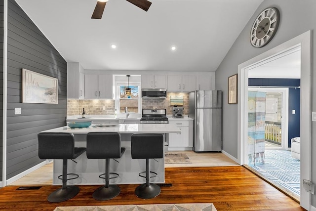 kitchen featuring vaulted ceiling, light countertops, light wood-type flooring, and appliances with stainless steel finishes