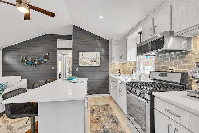 kitchen with light countertops, a sink, a kitchen island, a breakfast bar, and appliances with stainless steel finishes