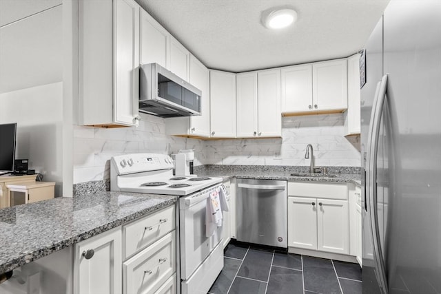 kitchen featuring sink, dark tile patterned floors, white cabinetry, stainless steel appliances, and light stone countertops