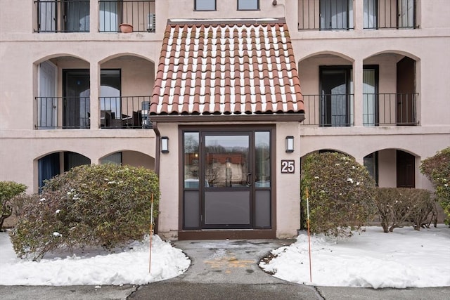 snow covered property entrance featuring a balcony