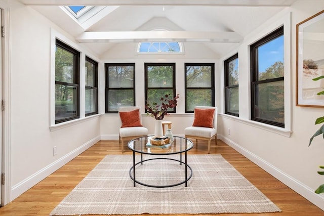 sunroom / solarium with baseboards, lofted ceiling with skylight, and wood finished floors