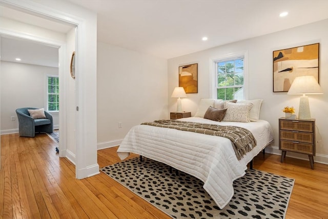 bedroom featuring multiple windows, light wood-style floors, and baseboards