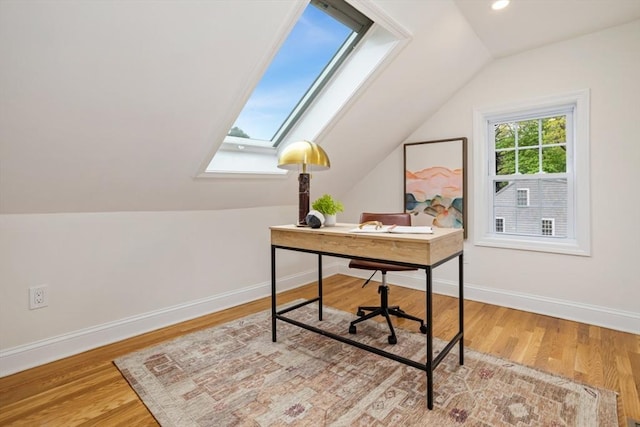 home office with lofted ceiling with skylight, baseboards, and wood finished floors