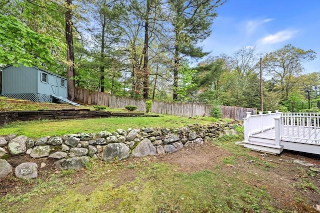 view of yard featuring a deck, an outdoor structure, a shed, and a fenced backyard