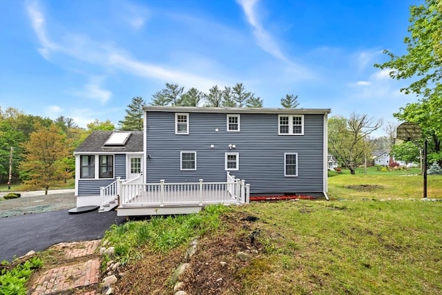 rear view of property featuring a wooden deck and a lawn