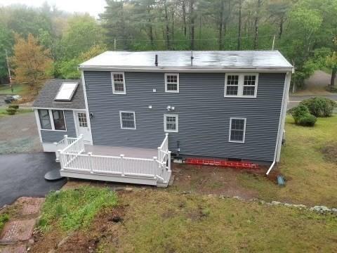 back of house featuring a yard, a forest view, and a deck