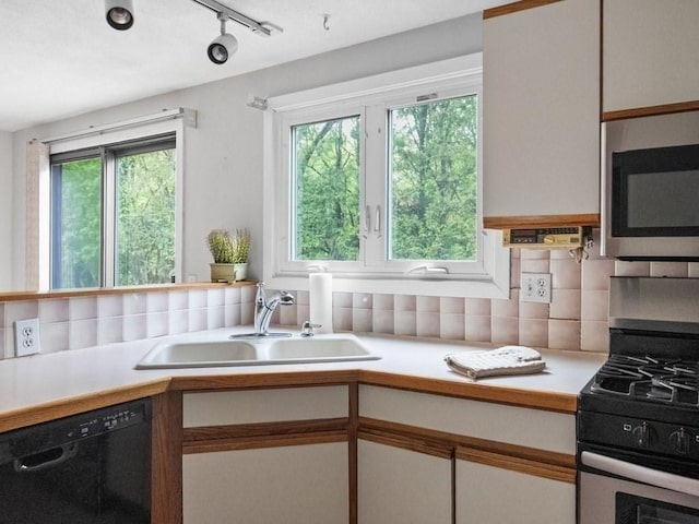 kitchen featuring appliances with stainless steel finishes, a sink, light countertops, and healthy amount of natural light