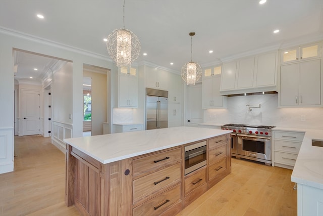 kitchen featuring high quality appliances, pendant lighting, a spacious island, decorative backsplash, and white cabinets