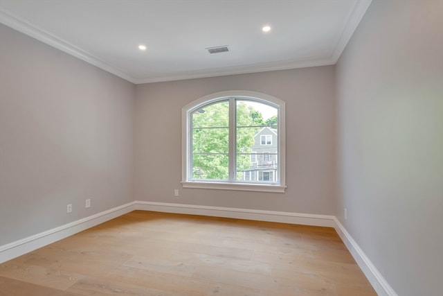 empty room with ornamental molding and light hardwood / wood-style flooring