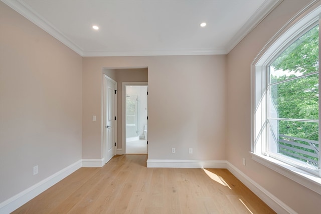 spare room featuring ornamental molding, a wealth of natural light, and light hardwood / wood-style flooring