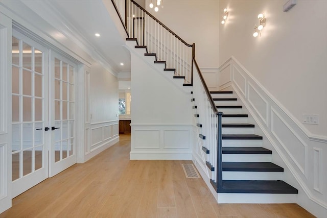 stairs featuring hardwood / wood-style flooring, crown molding, and french doors