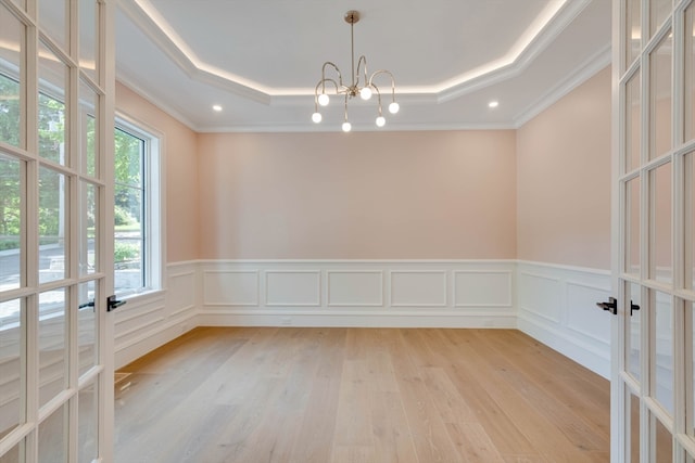 spare room with plenty of natural light, light hardwood / wood-style floors, ornamental molding, and a tray ceiling