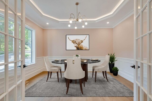 unfurnished room with french doors, light wood-type flooring, a tray ceiling, and crown molding