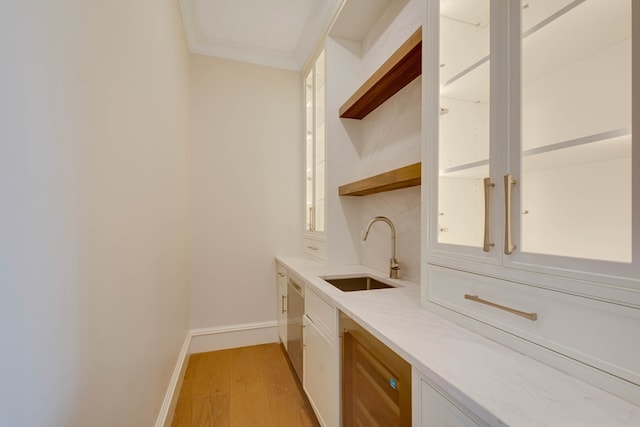 bar featuring light stone countertops, crown molding, sink, white cabinets, and light hardwood / wood-style floors