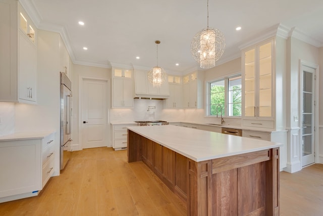 kitchen with white cabinets, built in fridge, sink, hanging light fixtures, and a large island