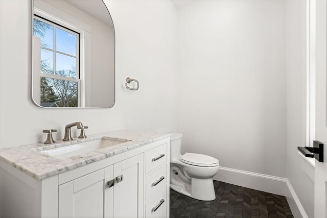 bathroom with toilet, baseboards, and vanity