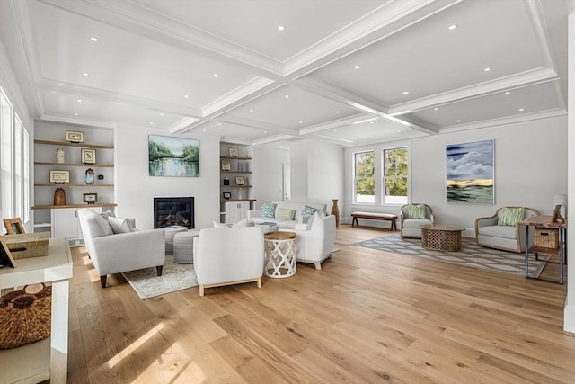 living room featuring light wood finished floors, coffered ceiling, a glass covered fireplace, ornamental molding, and beamed ceiling