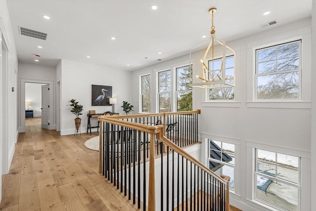 corridor with recessed lighting, visible vents, light wood-style flooring, an upstairs landing, and baseboards