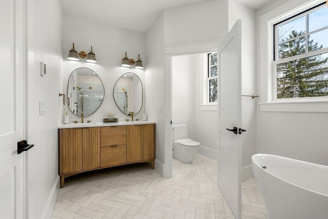 full bath featuring double vanity, a freestanding tub, baseboards, and toilet