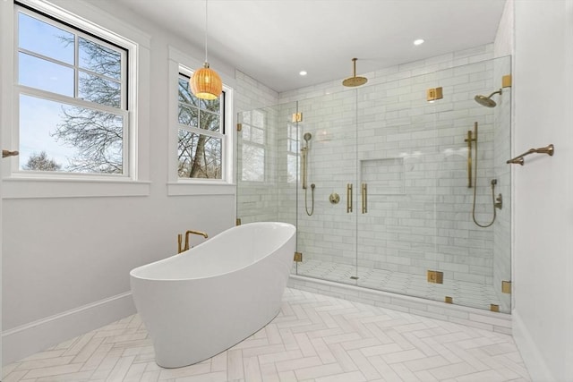 full bathroom featuring a freestanding tub, plenty of natural light, baseboards, and a stall shower