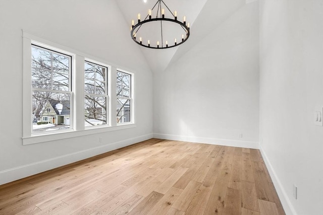 unfurnished dining area featuring light wood-type flooring, high vaulted ceiling, baseboards, and a notable chandelier
