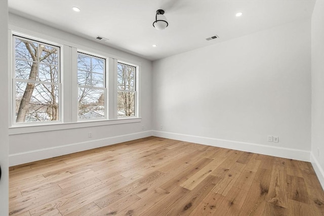 empty room with light wood-style floors, recessed lighting, visible vents, and baseboards